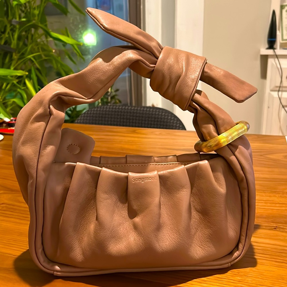 Mini bag from Songmont and its material is leather. Color is creamy pink.